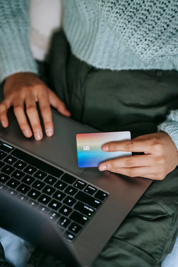 Close-up of a person using a credit card for online shopping with a laptop indoors.